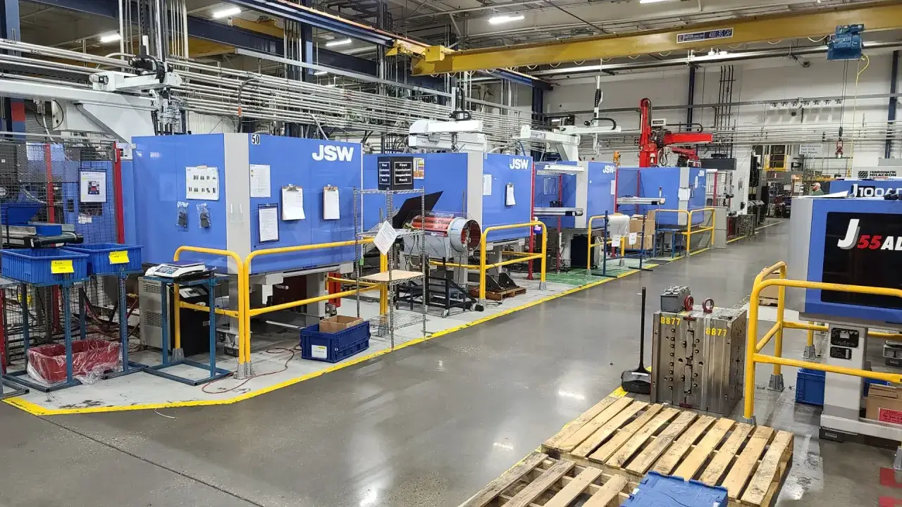 Factory floor with multiple JSW injection molding machines, ready to produce plastics for electronics.