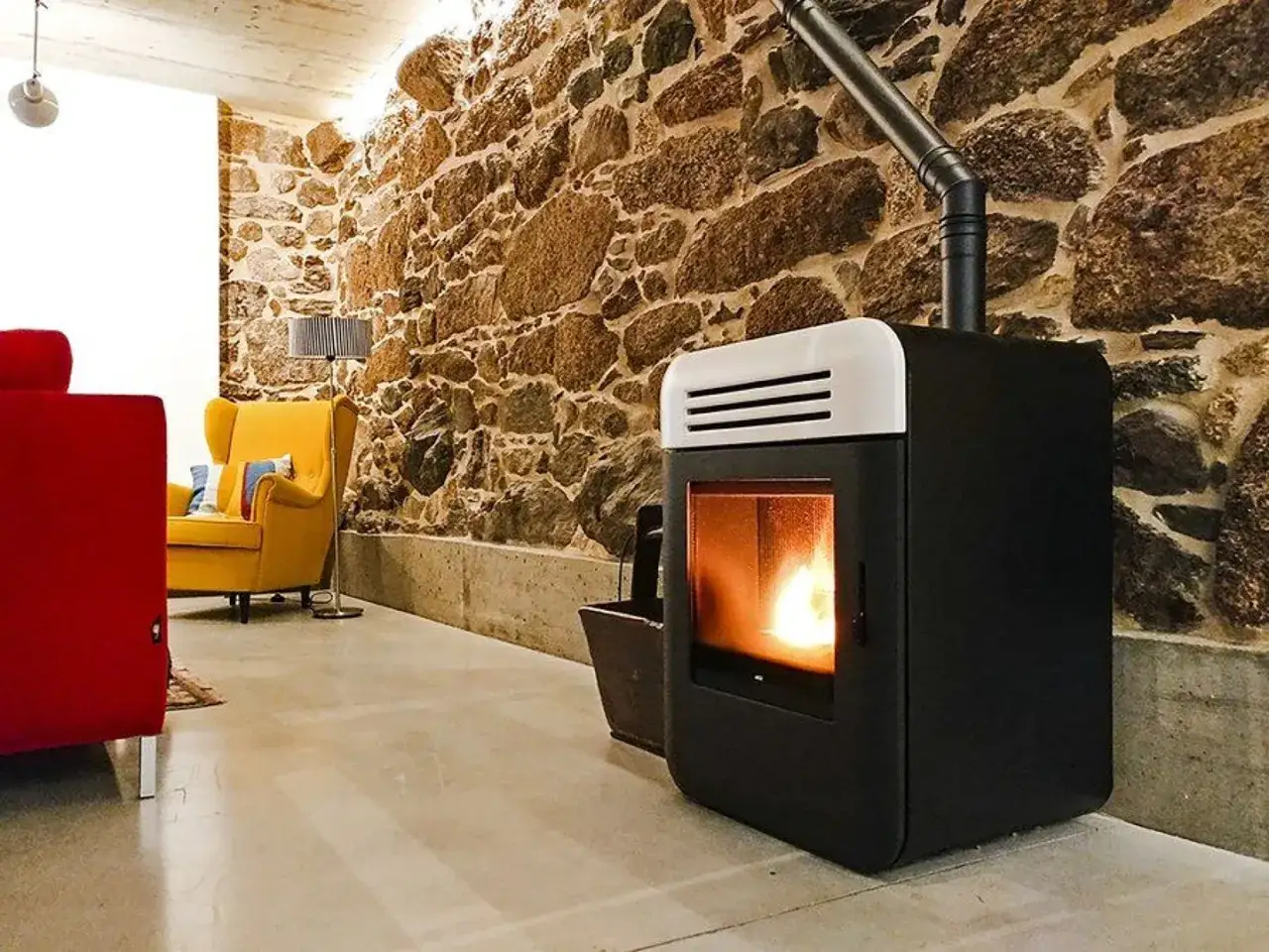 Estufa moderna de pellets, que son los pellets, calienta un salón rústico con pared de piedra y muebles coloridos.