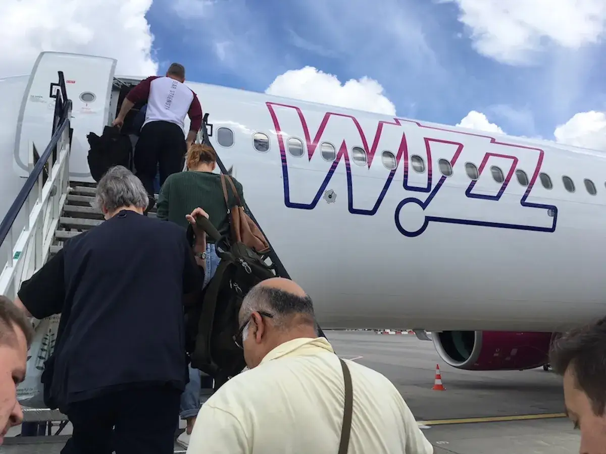 Pasażerowie wchodzą po schodkach do samolotu Wizz Air. Wizz priority to szybkie wejście na pokład.
