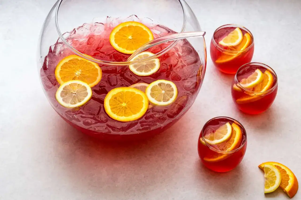 En stor sk&aring;l med r&ouml;d b&aring;l, fylld med is och skivor av apelsin och citron. Flera glas med samma b&aring;l st&aring;r bredvid. Ett perfekt b&aring;l recept f&ouml;r festen!