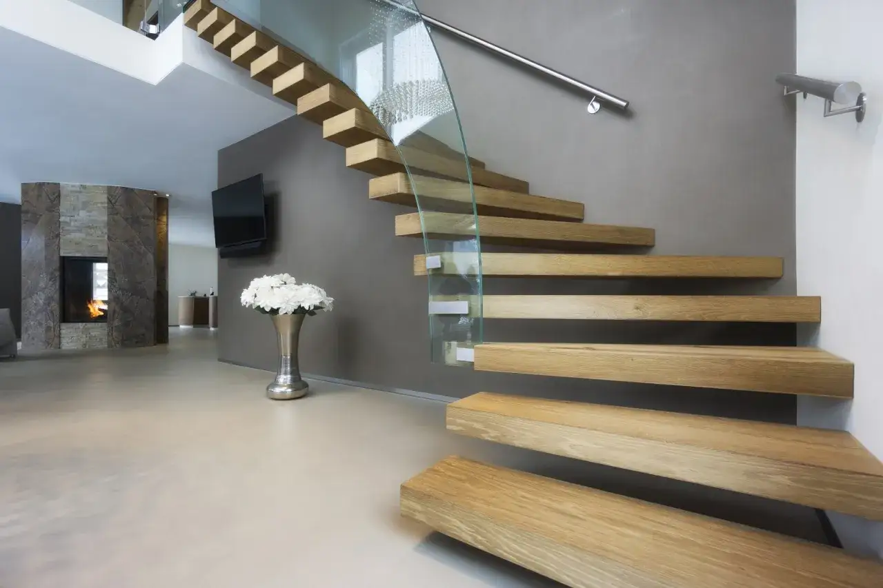 Nowoczesne schody dywanowe na beton, z drewnianymi stopniami i szklaną balustradą, tworzą lekkość i elegancję.