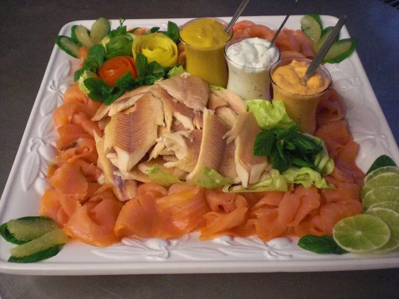 Eine festliche Fischplatte mit Räucherlachs, pochiertem Fisch, Dips und Limettenspalten. Perfekt, um eine Fischplatte selber zu machen!