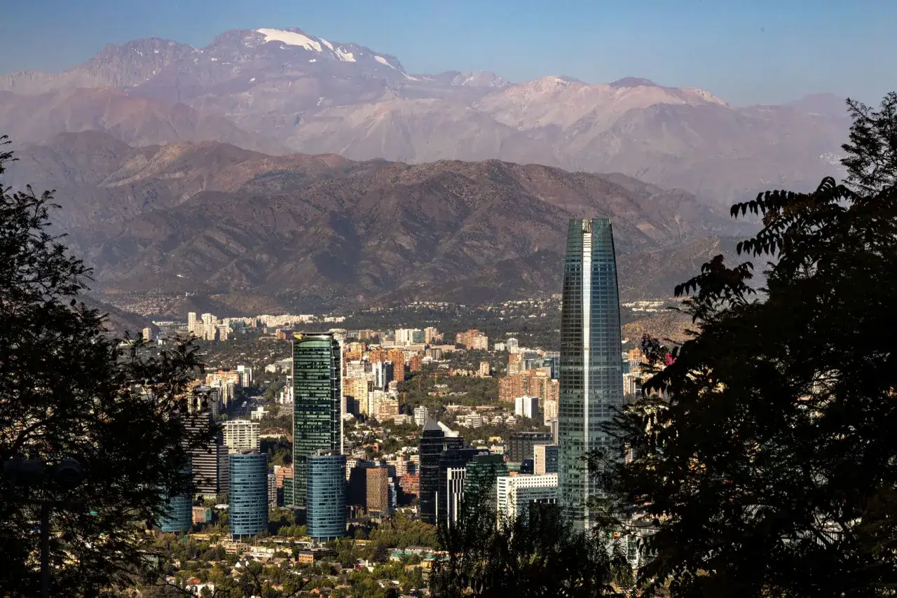Widok na nowoczesne wieżowce Santiago de Chile z ośnieżonymi Andami w tle.