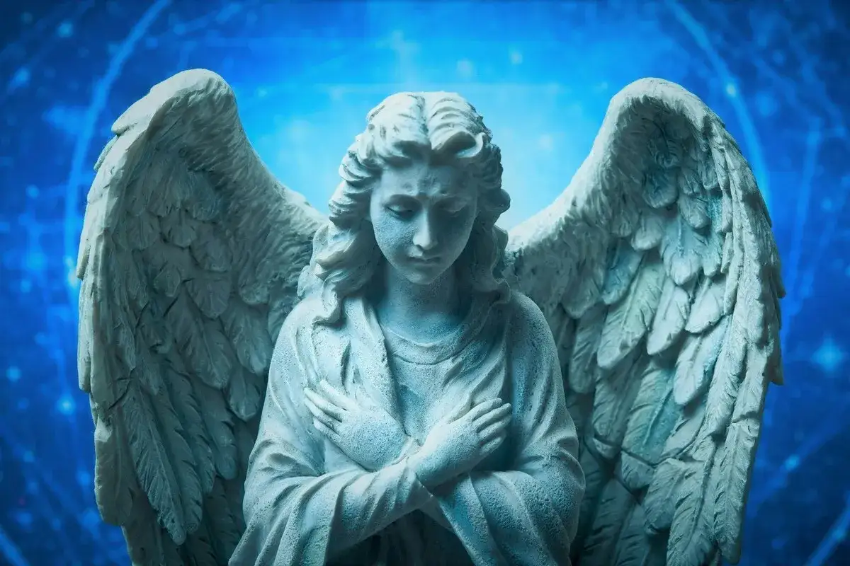 Kamienna rzeźba anioła ze złożonymi rękami na piersi. Jego skrzydła są szeroko rozpostarte. To inspiracja na horoskop anielski na jutro.