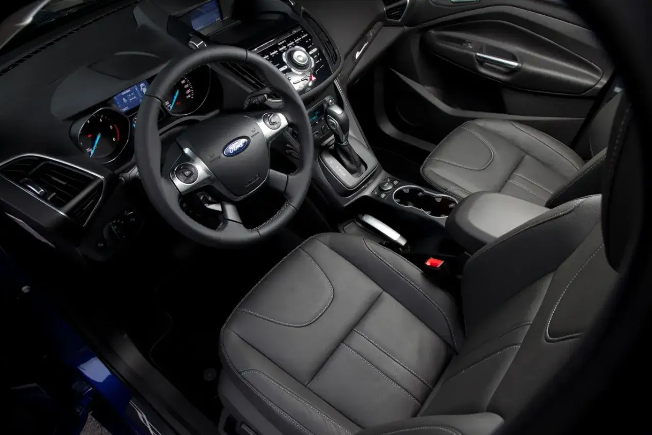 Wnętrze Ford Kuga 2: skórzana tapicerka, kierownica z przyciskami, deska rozdzielcza z ekranem i nawigacją.