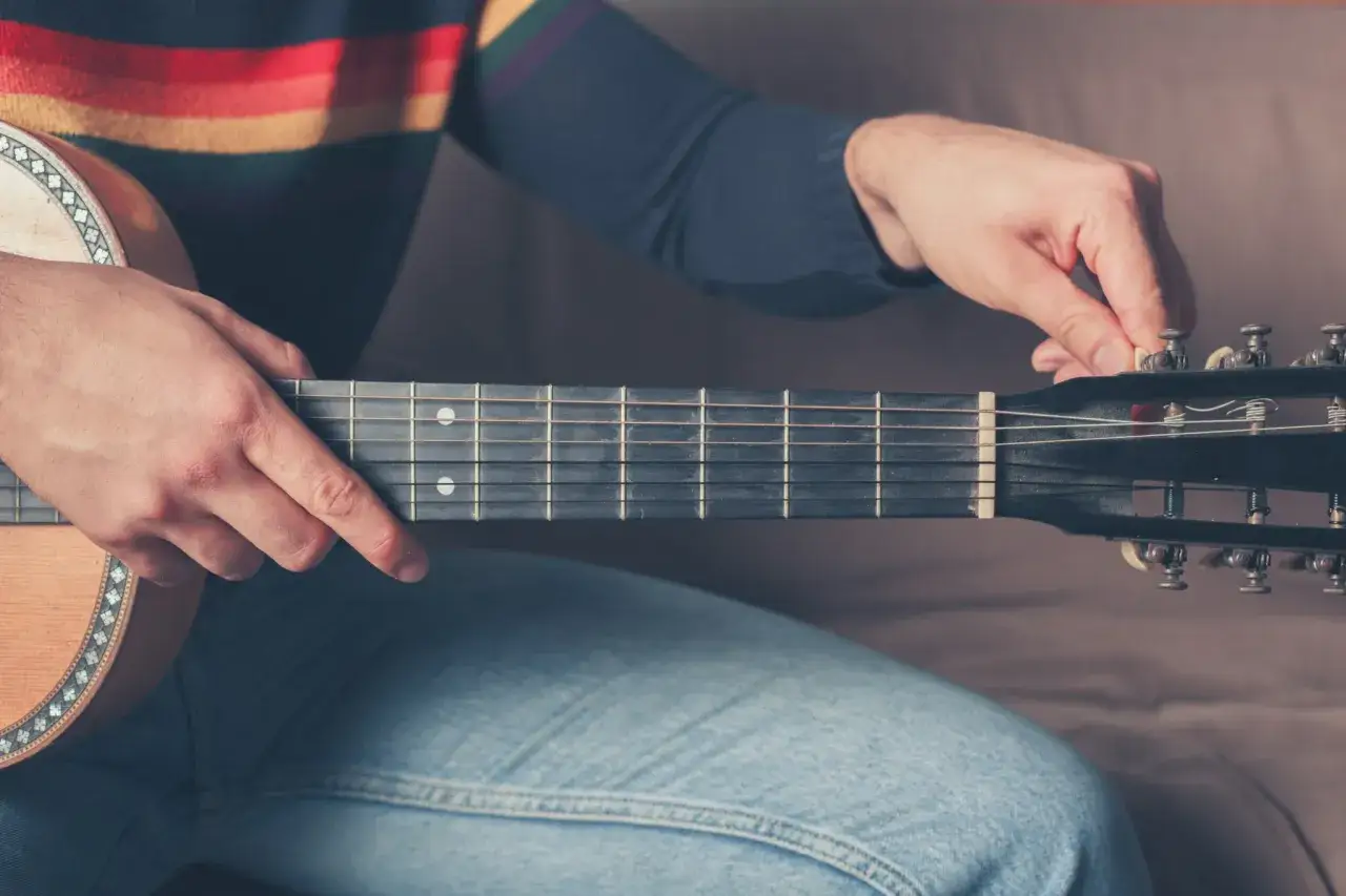 Dłoń stroi gitarę, przygotowując ją do gry w standardowym stroju C#.