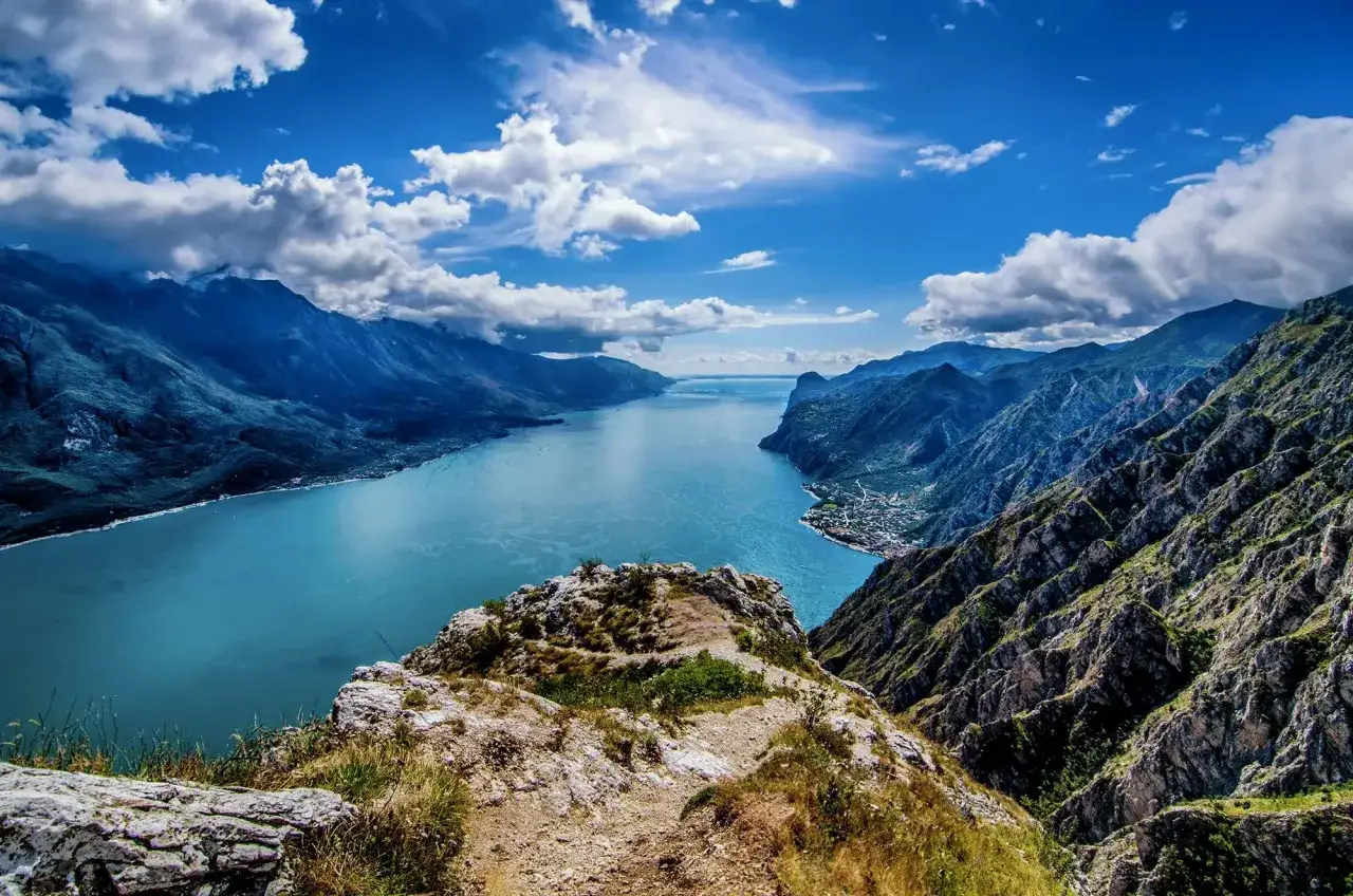Vista mozzafiato di una montagna vicino al Lago di Garda, con acque azzurre e cielo nuvoloso.