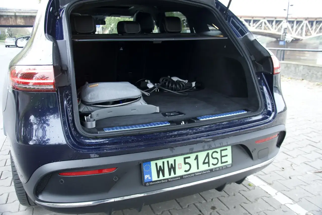 Bagażnik ciemnoniebieskiego Mercedes EQC z torbą i kablem do ładowania.