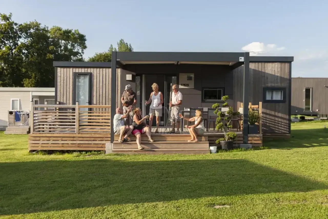 Un groupe d'amis profite d'un apéritif sur la terrasse d'une tiny house à l'année.
