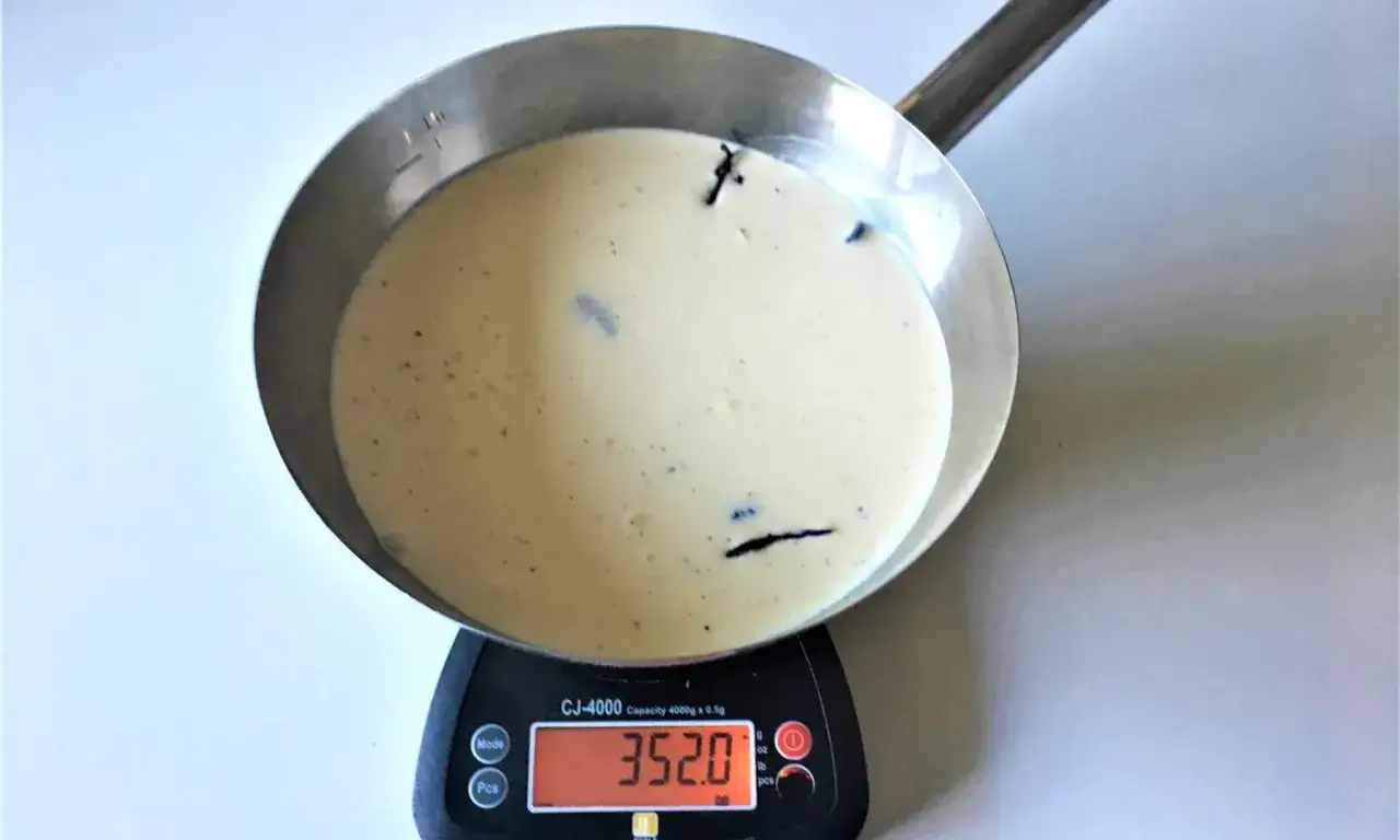 En kastrull med en kr&auml;mig blandning, kanske f&ouml;r ett glass grundrecept, st&aring;r p&aring; en v&aring;g som visar 352.0 gram.