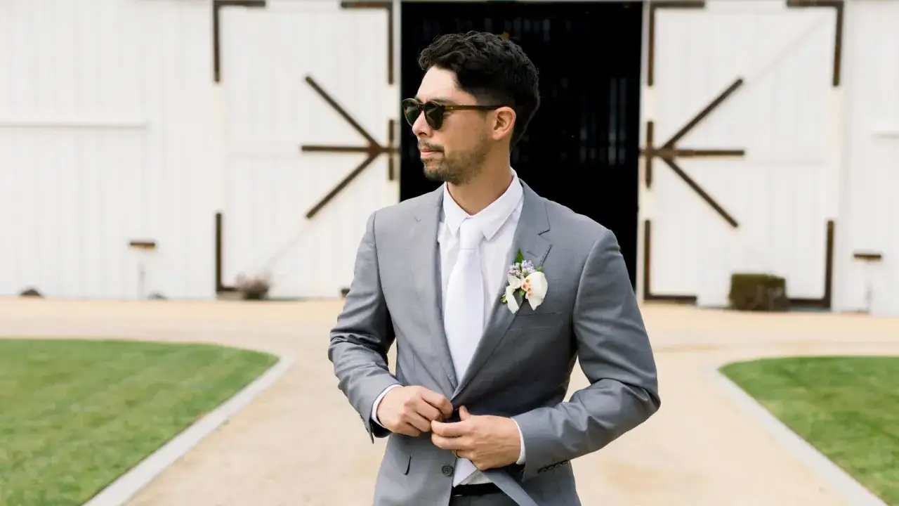 Sharp groom in a grey suit, white shirt, and tie. Perfect for summer wedding suit ideas.