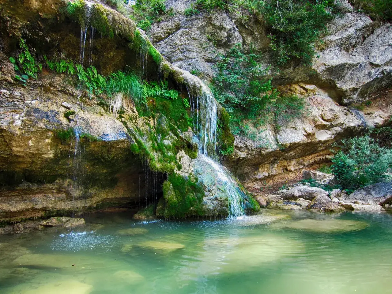 Cascada en la ruta 7 gorgs. Agua verde turquesa cae sobre rocas cubiertas de musgo.