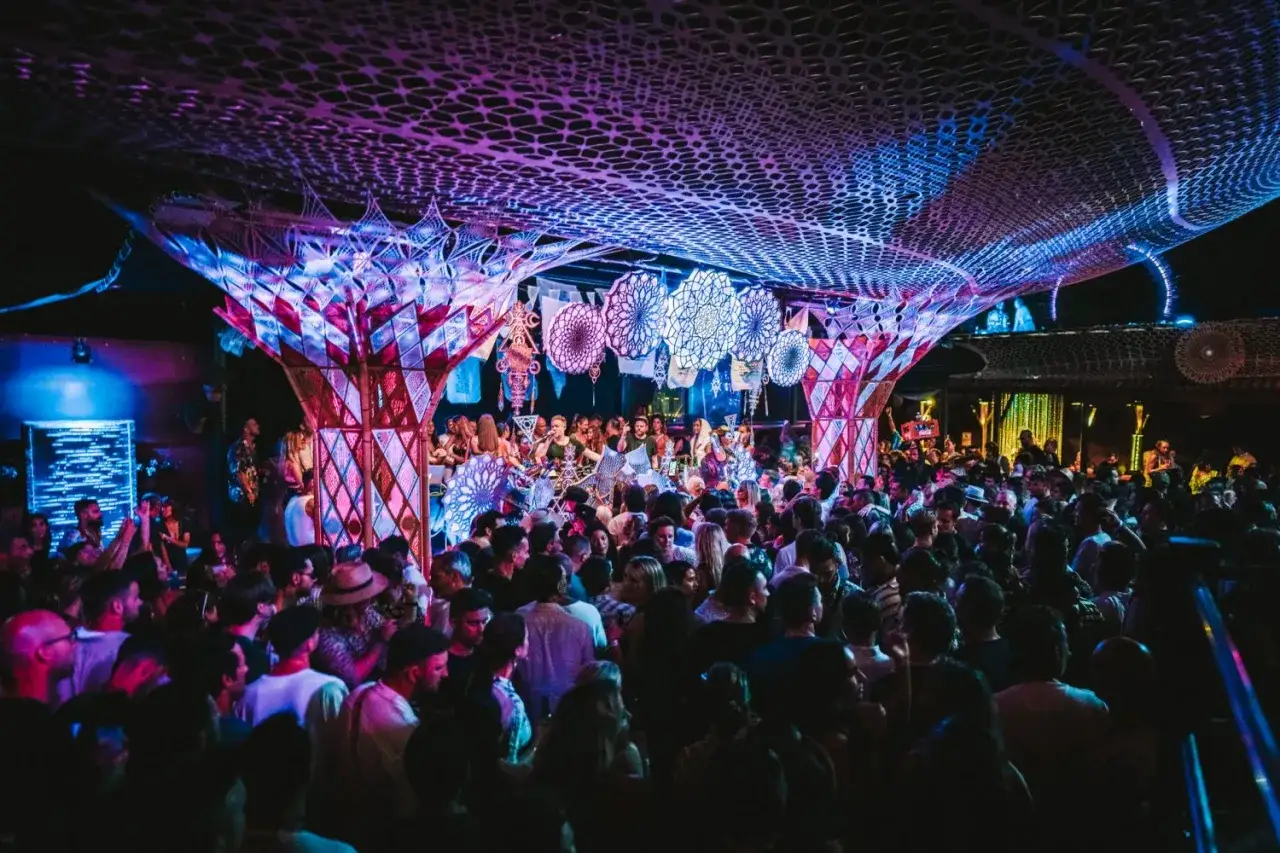 Folla in delirio per gli eventi di Ibiza a settembre. Luci psichedeliche e musica pulsante in un locale notturno.