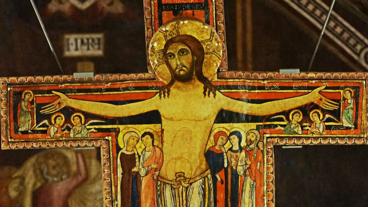 Stary krzyż franciszkański z malowanymi postaciami Jezusa, aniołów i świętych.