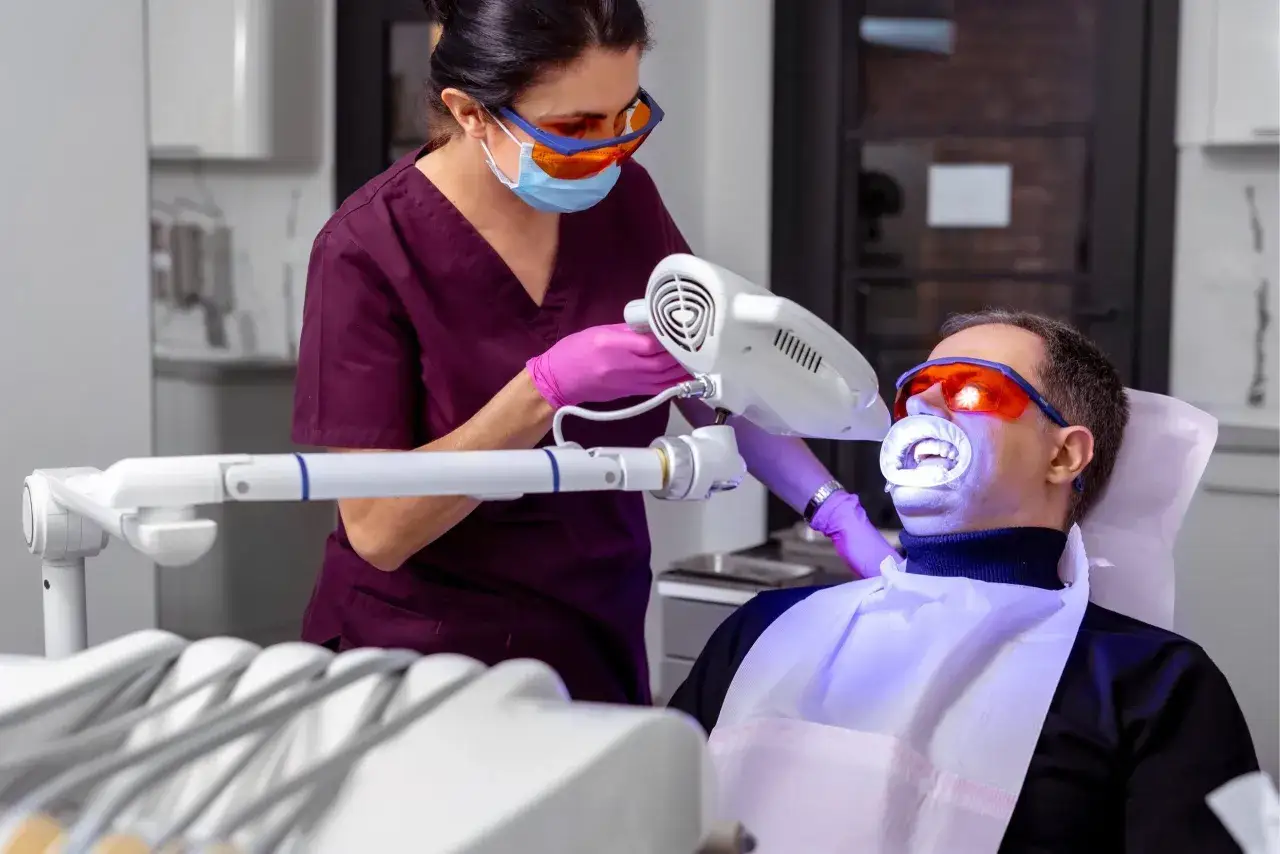 Dentystka używa lampy do wybielania zębów. Czy woda utleniona wybiela zęby? Tutaj profesjonalny zabieg rozjaśnia uśmiech.