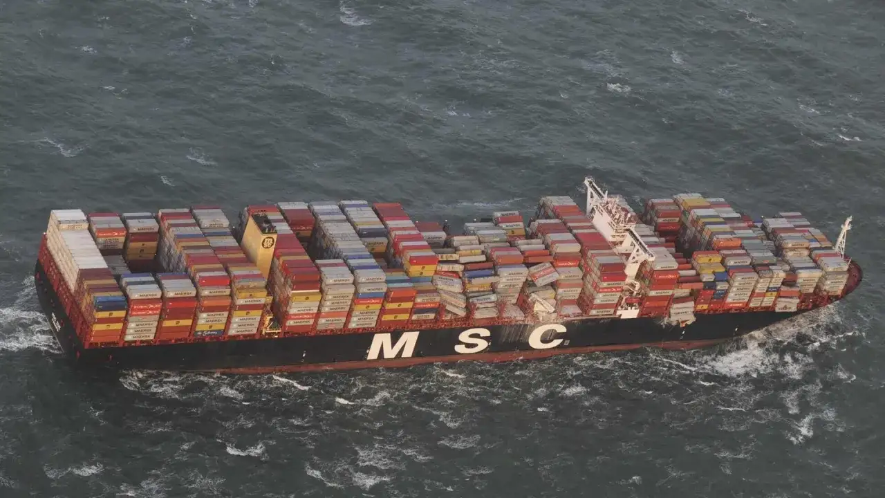 Ein riesiges Containerschiff der MSC fährt durch raue See. Die Ladung, ein allgemeiner Durchschnitt von Waren, ist hoch gestapelt.
