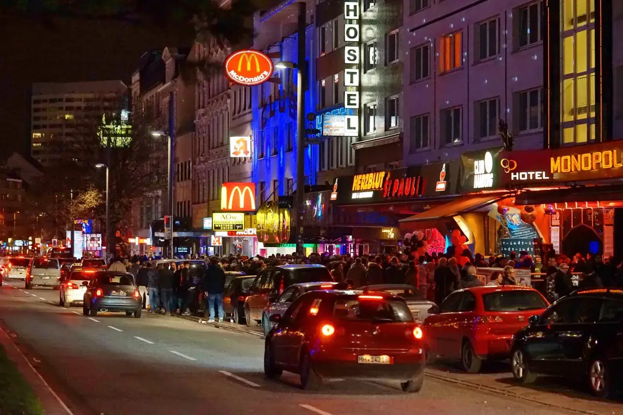 Nachts ist die Reeperbahn in der Woche belebt. Autos stauen sich, Menschen schlendern vorbei an leuchtenden Schildern von McDonald's, Hostels und Clubs.