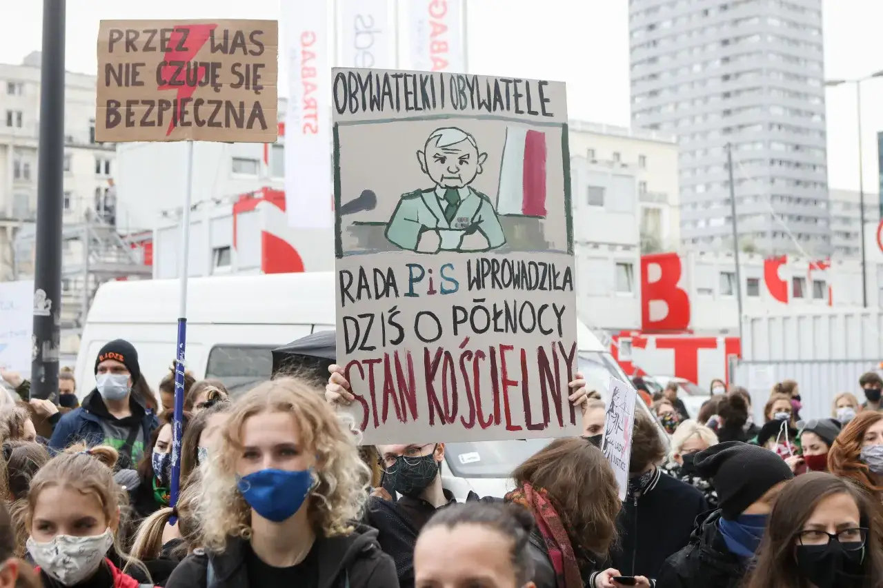 Ludzie na proteście w Polsce niosą transparenty wyrażające niezadowolenie. Jeden z nich głosi: