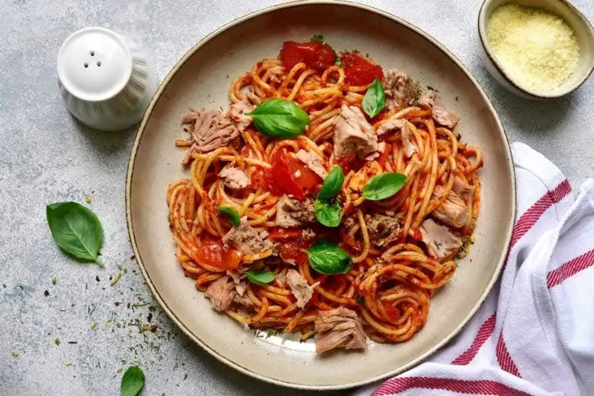 Un piatto invitante di spaghetti al tonno con pomodoro fresco e basilico, pronto per essere gustato.