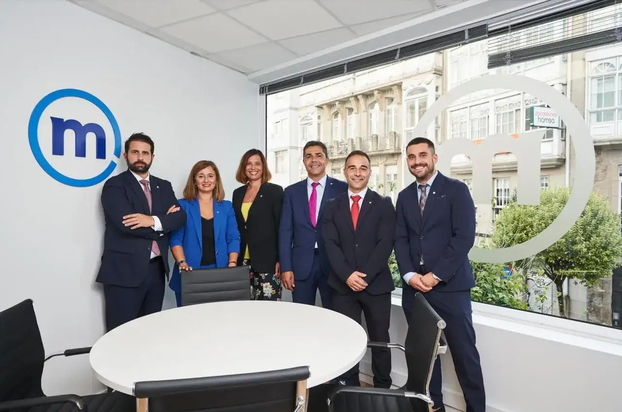 Equipo profesional posando frente al logo de Mediolanum. Buscando banco Mediolanum opiniones, aquí tienes un vistazo a su equipo.