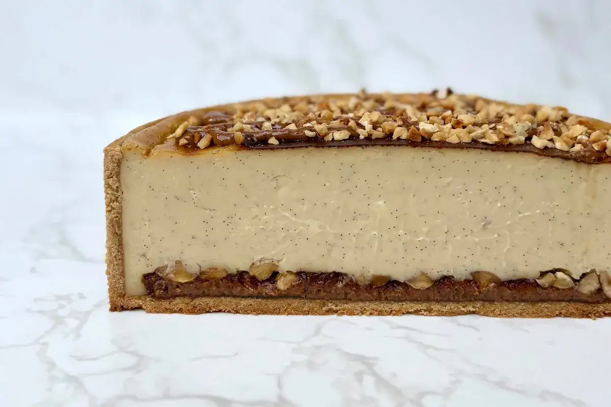 Tranche d'un flan pralin&eacute; onctueux, garni de noisettes concass&eacute;es et d'un coulis de caramel.