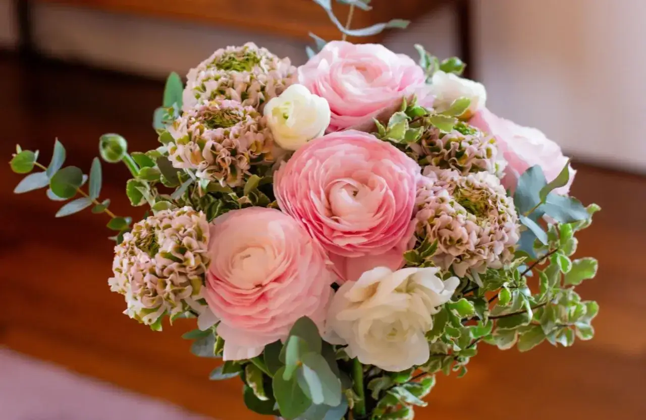 Un bouquet de fleurs roses et blanches, avec des touches de verdure, prêt à être ajouté à la liste de souhaits du fleuriste.