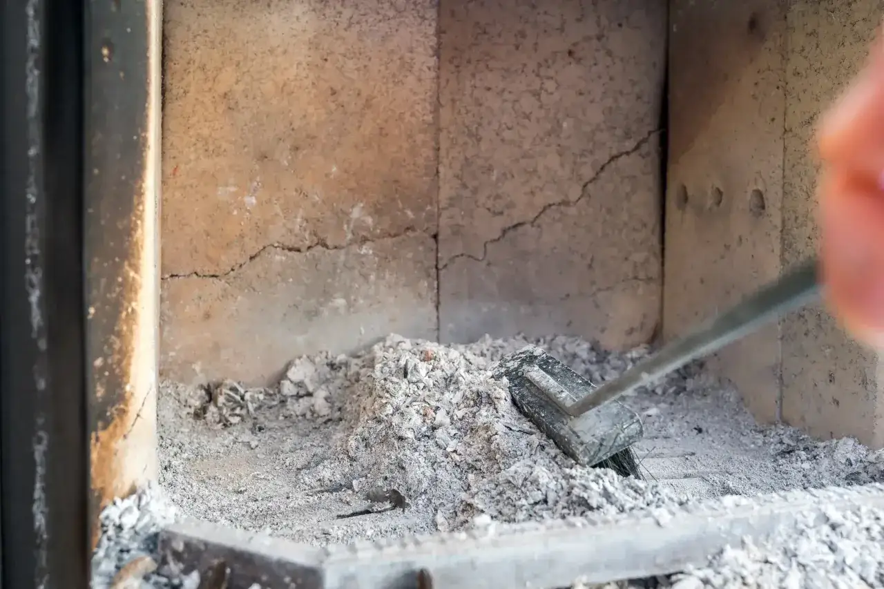 Asche im Kamin, trotz kaputter Schamottsteine wird weiter geheizt.