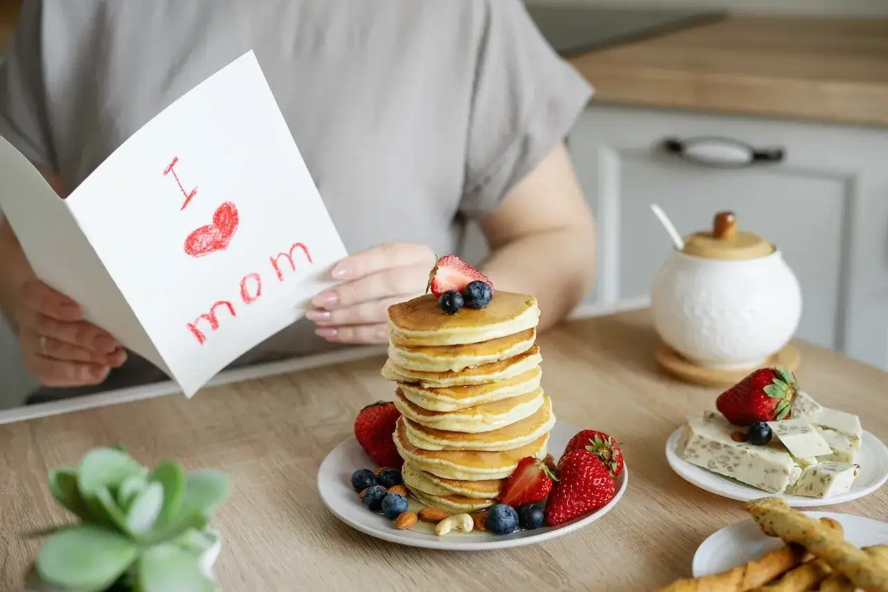 Ein Stapel Buttermilch-Pancakes mit Beeren und Nüssen, daneben eine Karte mit 