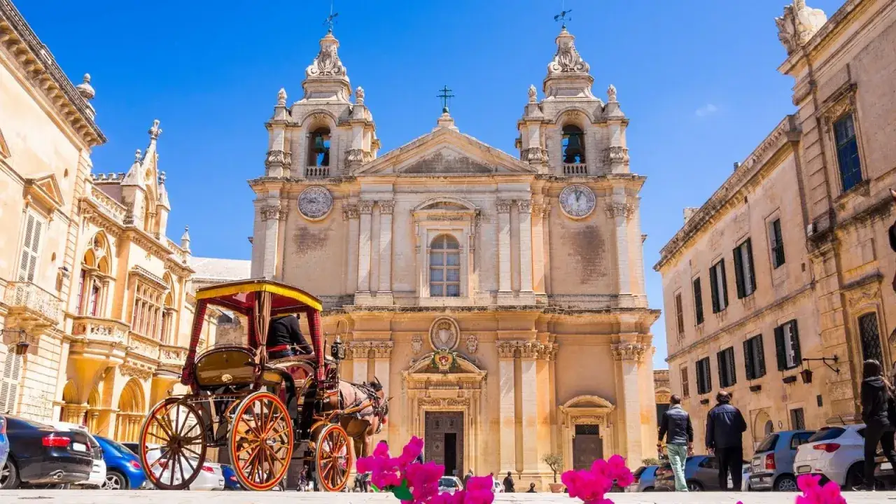 Urokliwe miasteczko Mdina na Malcie. Konny powóz czeka przed katedrą, a w tle widać zabytkowe kamienice.