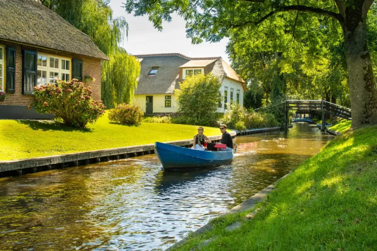 Ein Paar f&auml;hrt mit einem blauen Boot durch einen Kanal im 