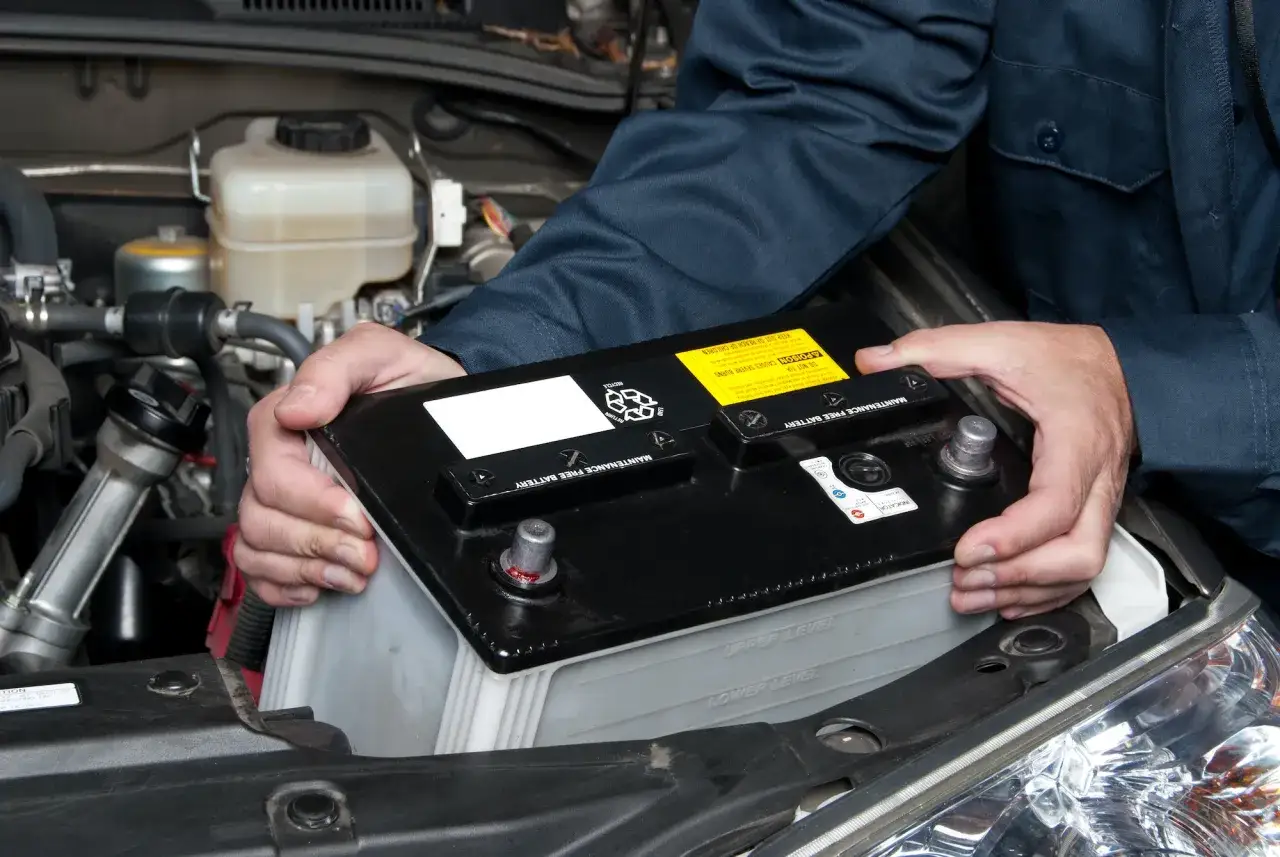 Mec&aacute;nico instalando una bater&iacute;a nueva en un coche. Averigua cuanto cuesta cambiar la bateria del coche.