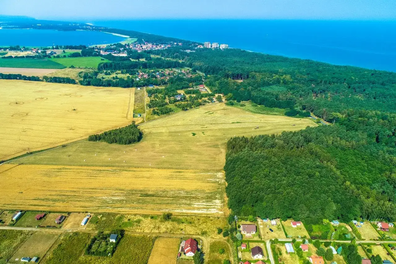 Krajobraz nadmorski z polami uprawnymi, lasem i zabudowaniami. Zastanawiasz się, ile kosztuje zmiana planu zagospodarowania przestrzennego?