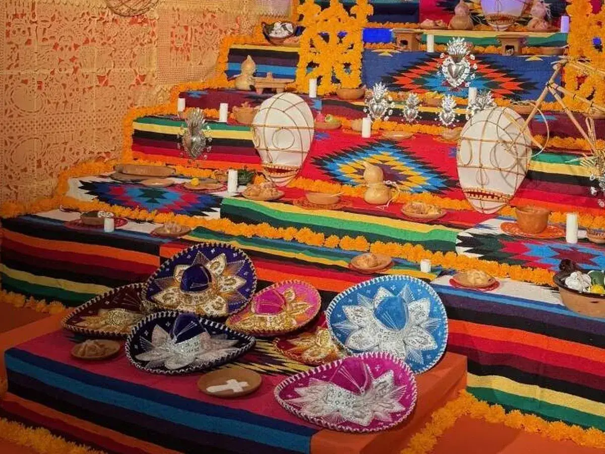 Un vibrante altar de los muertos en una casa de México, adornado con sombreros, flores de cempasúchil y ofrendas.