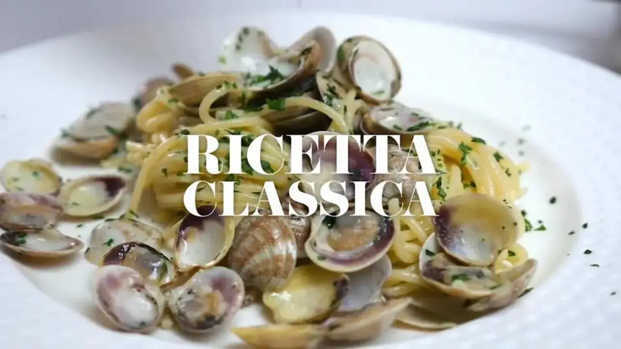 Spaghetti alle vongole, un classico intramontabile, serviti su un piatto bianco con prezzemolo tritato.