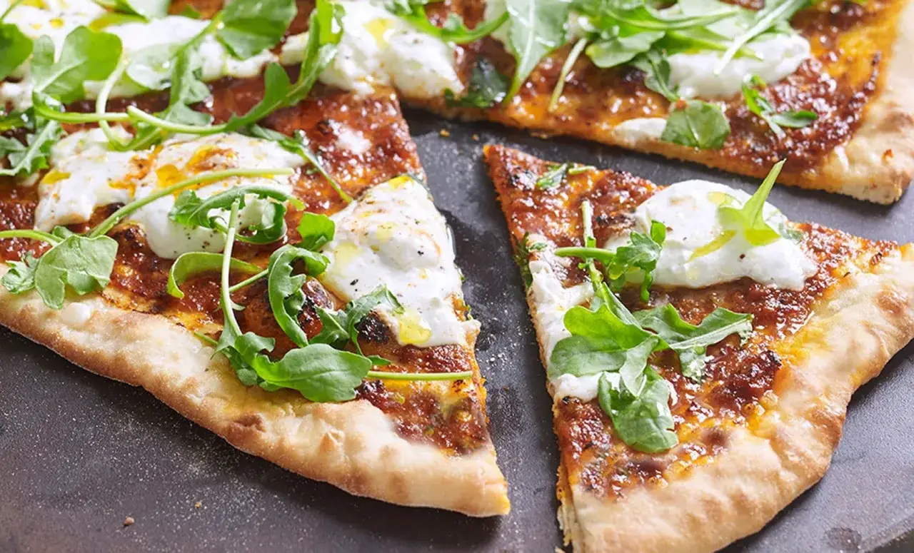 Eine köstliche Nduja Pizza mit cremigem Mozzarella und frischem Rucola, bereit zum Genießen.