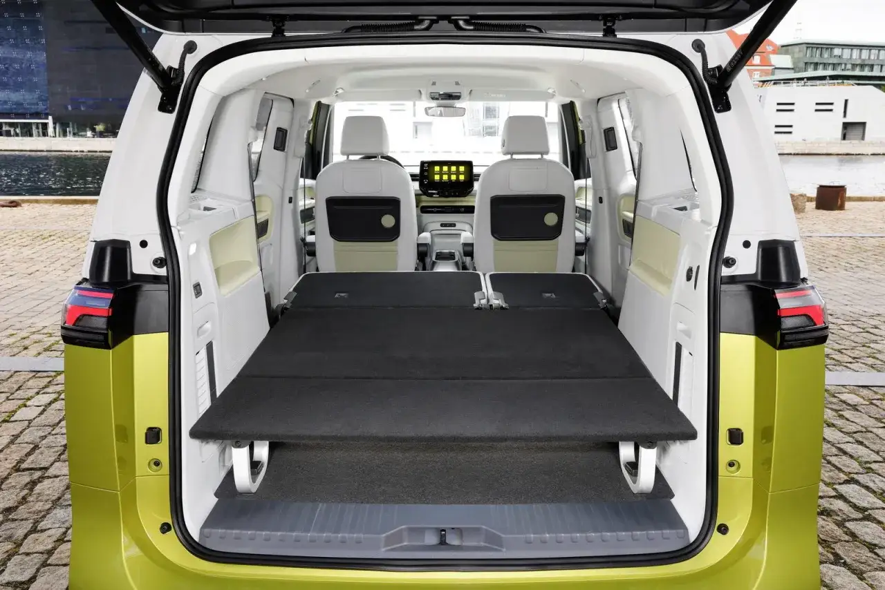 Interno del Volkswagen ID. Buzz con sedili posteriori abbassati per creare un letto. Spazio per avventure!
