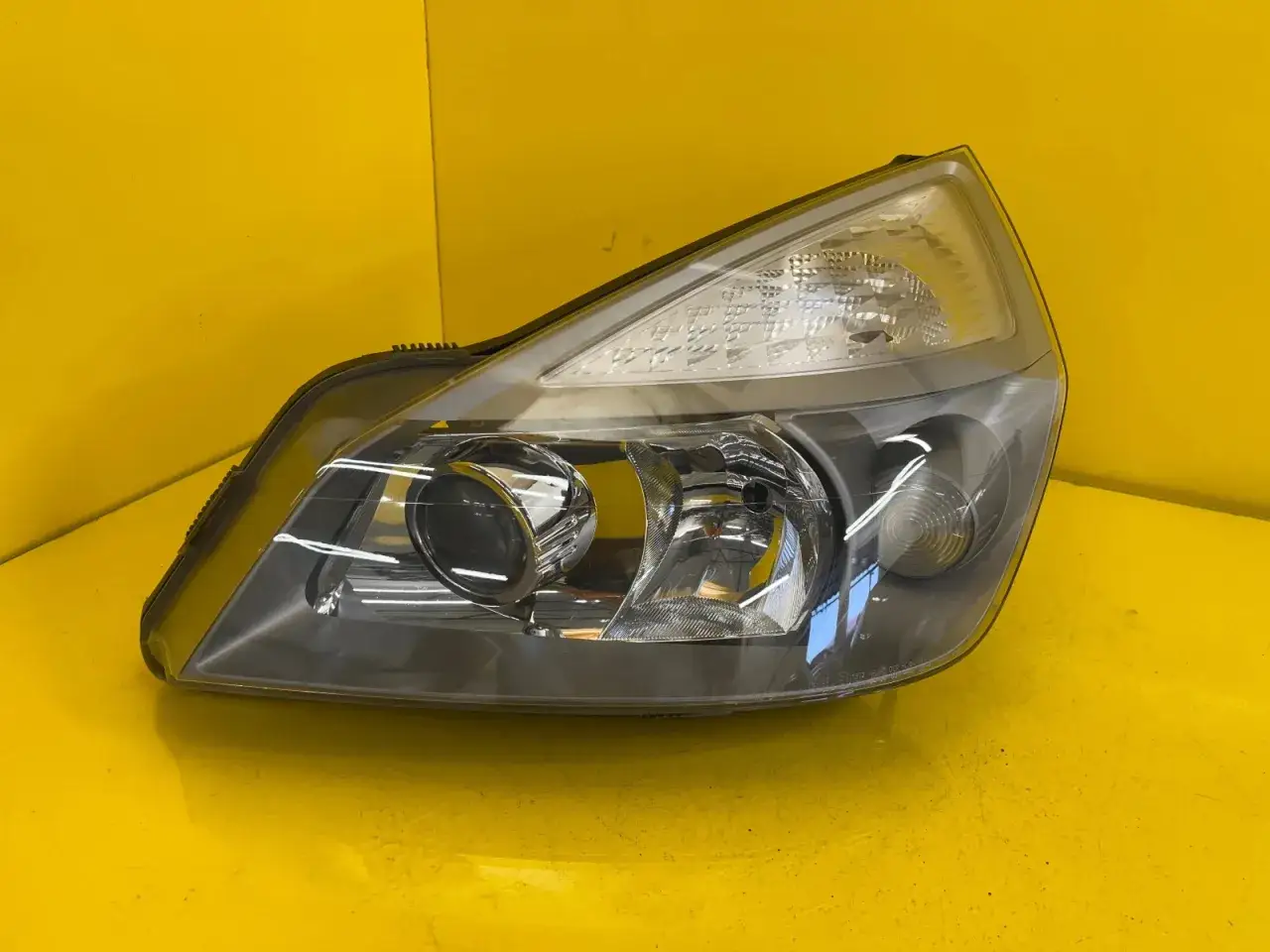 Reflektor do Renault Espace 4, gotowy do montażu, z błyszczącymi elementami i przezroczystym kloszem.
