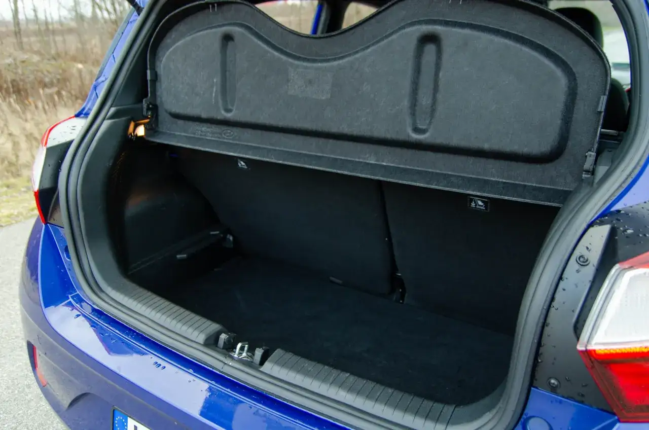Błękitny Hyundai i10 z otwartym bagażnikiem. Wnętrze jest puste, gotowe na pakowanie.