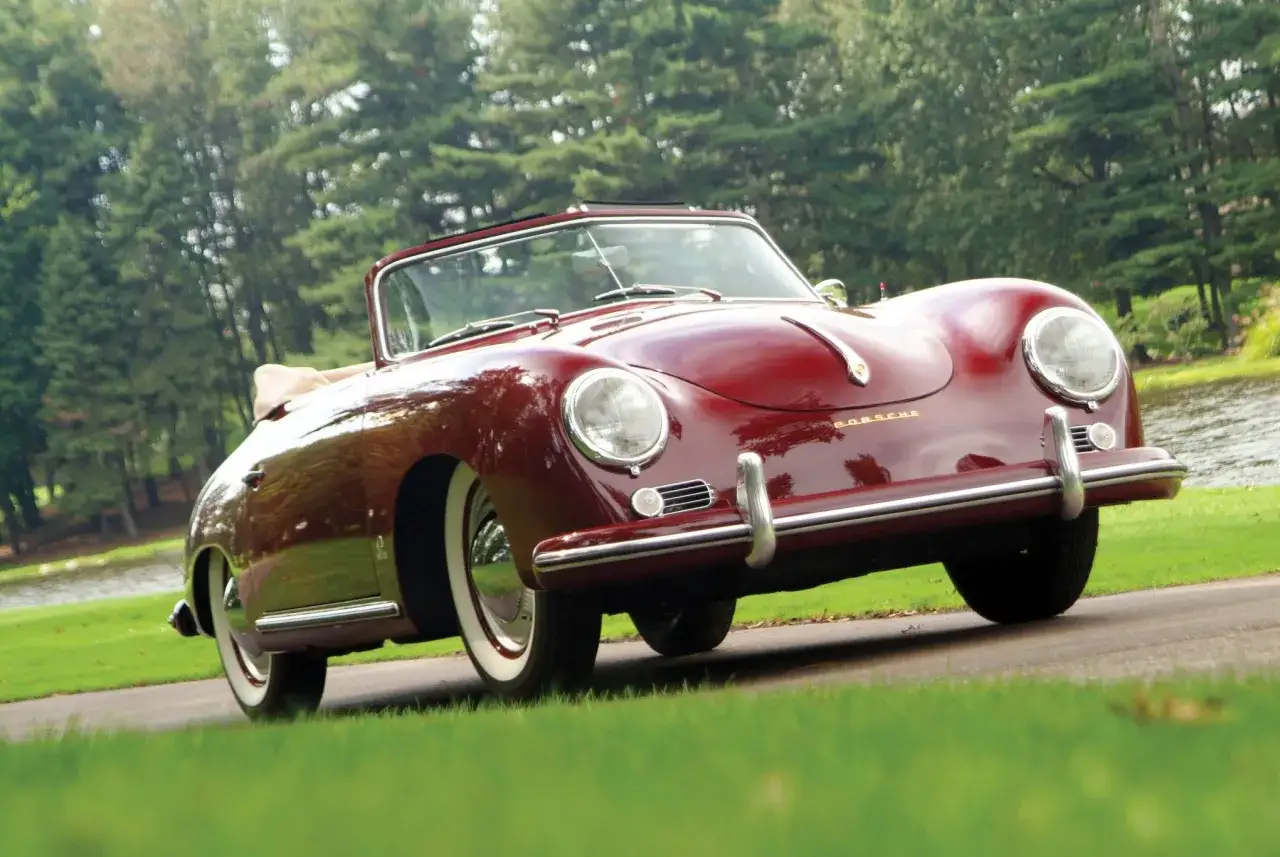 Czerwony kabriolet Porsche 356 z lat 50. na tle zieleni.