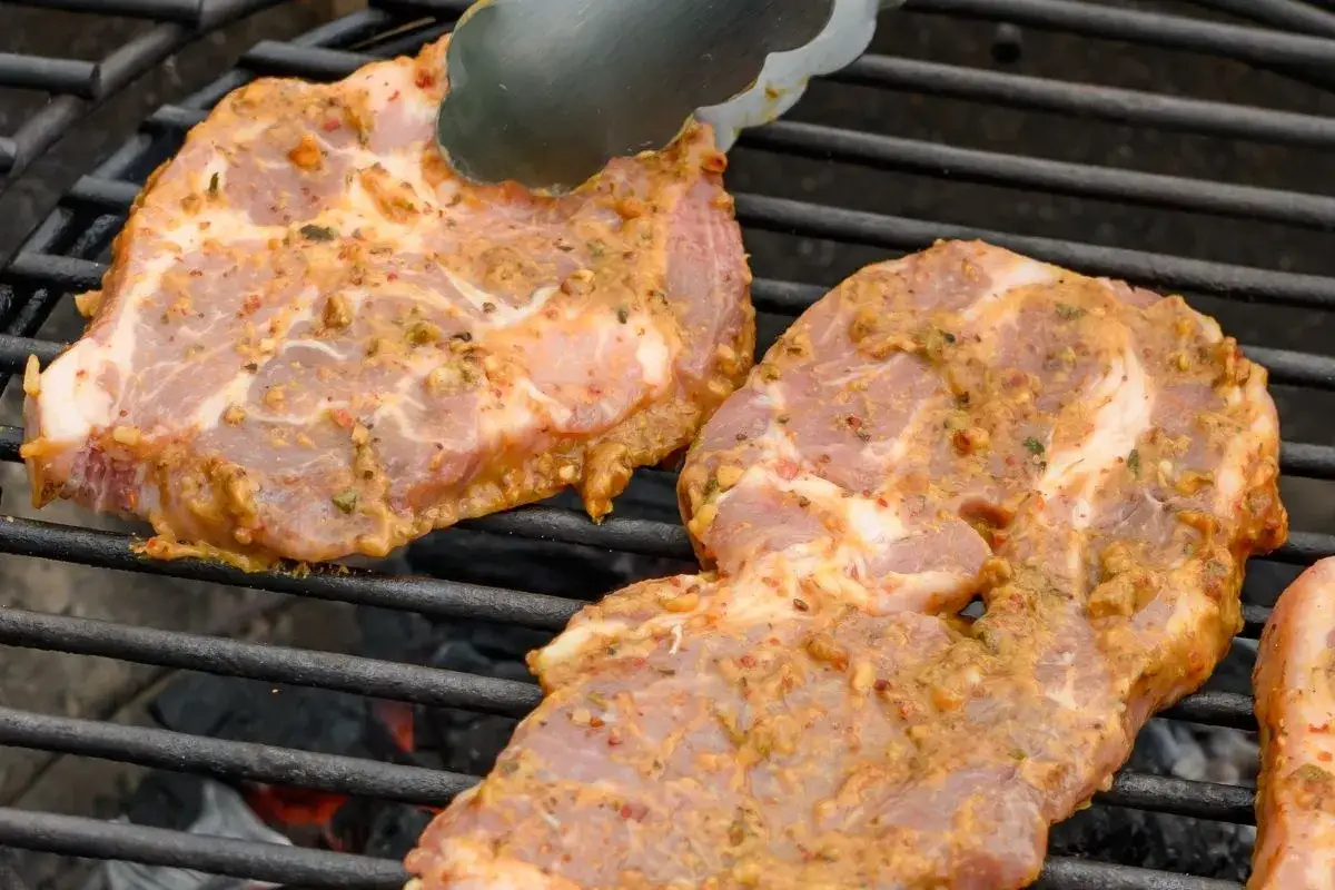 Schab na grilla w aromatycznej marynacie, przygotowany do pieczenia na rozżarzonych węglach.