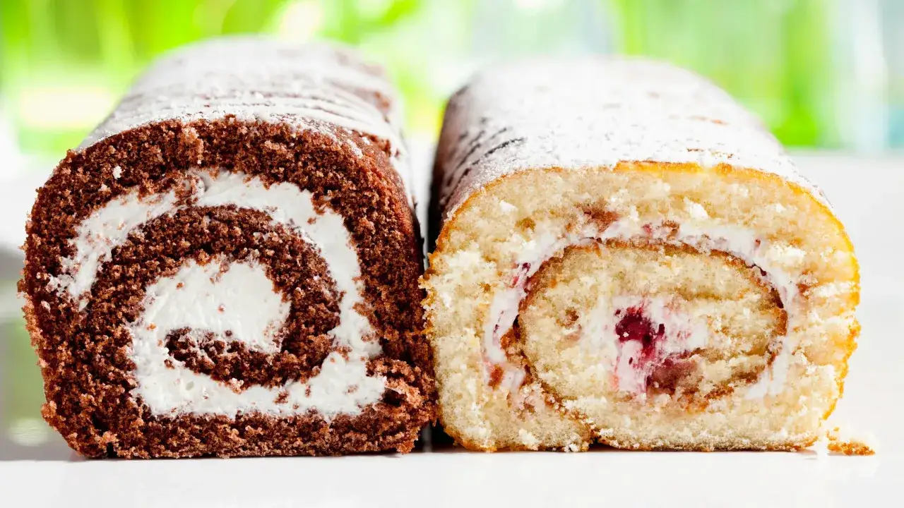 Zwei Biskuitrollen, eine Schoko- und eine helle Variante, mit Puderzucker best&auml;ubt. Ein leckeres biskuitrolle rezept zum Nachbacken.
