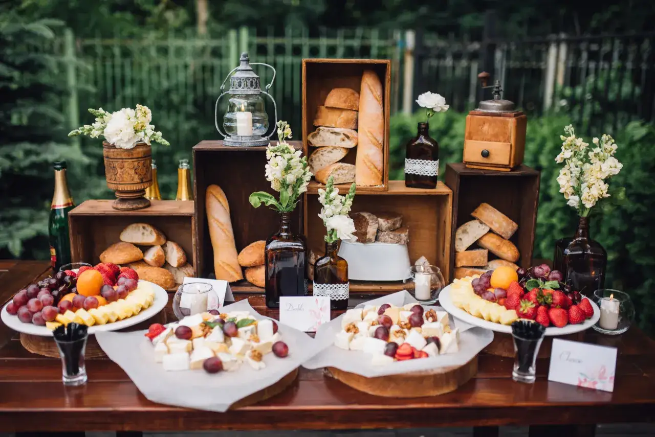 Buffet rustique avec pains, fromages, fruits et fleurs. Une belle idée repas baptême champêtre.