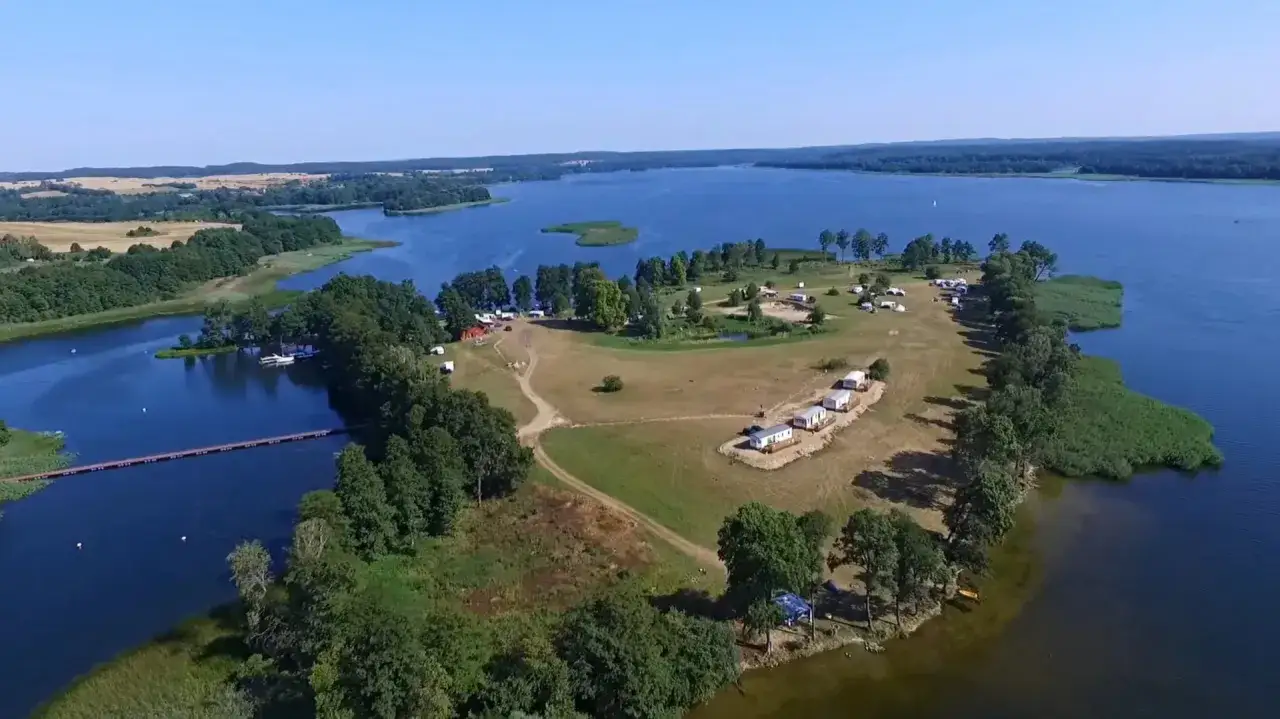 Malowniczy camping inter nos nad jeziorem, z domkami, przyczepami i pomostem. Idealne miejsce na wypoczynek.