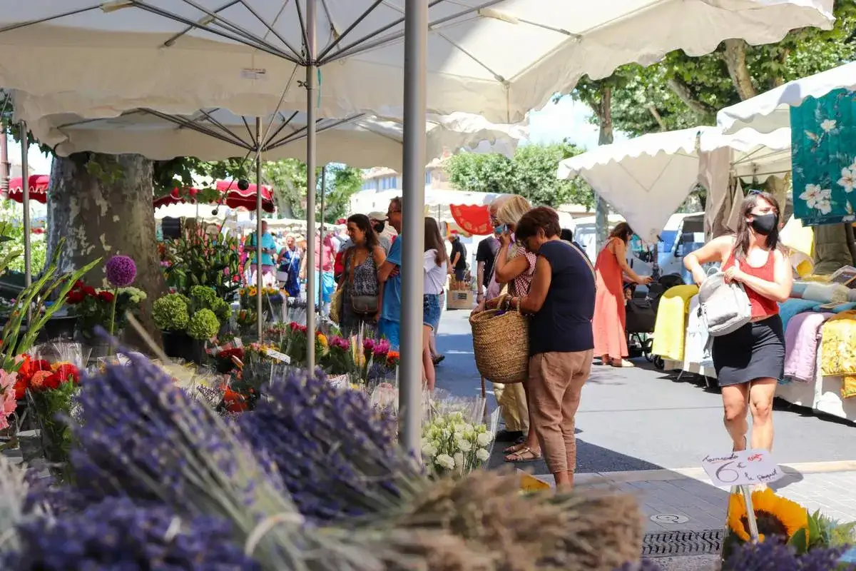 Ambiance anim&eacute;e au march&eacute; de Cereste. Des bouquets de lavande et des fleurs color&eacute;es invitent &agrave; la fl&acirc;nerie sous les parasols.