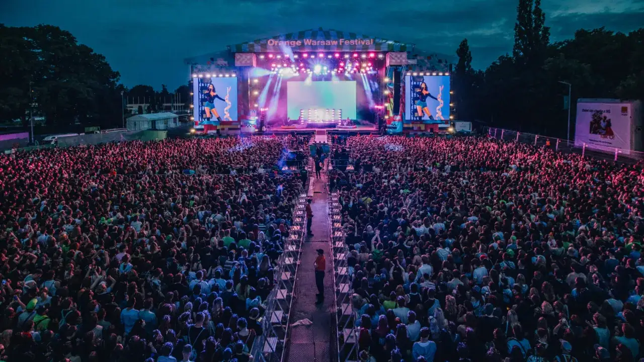 Tłum ludzi na Orange Warsaw Festival 2026, oświetlony sceną i ekranami.
