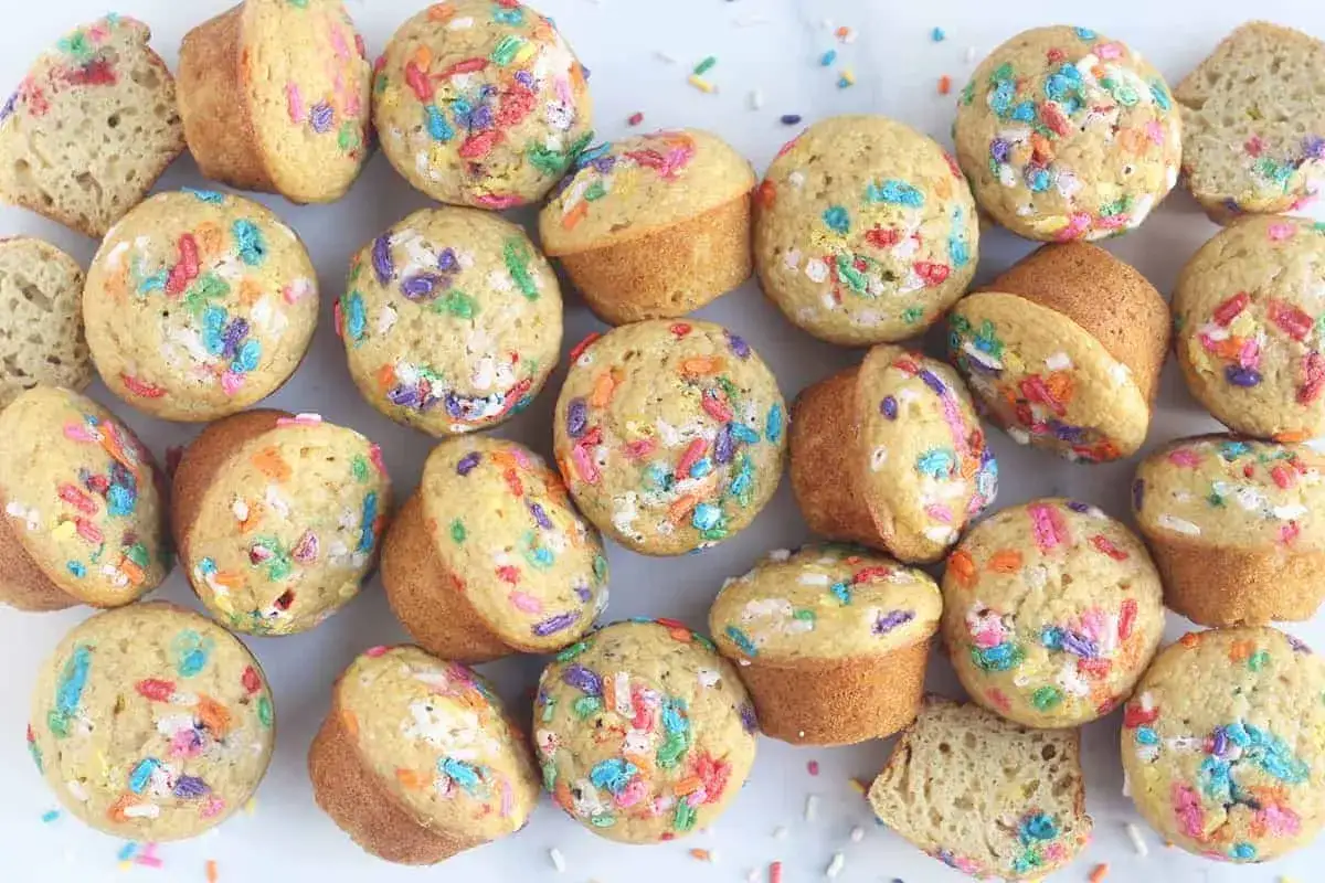 Bunte Muffins mit Streuseln, perfekt f&uuml;r einen Kindergeburtstag. Einige sind angeschnitten und zeigen den lockeren Teig.