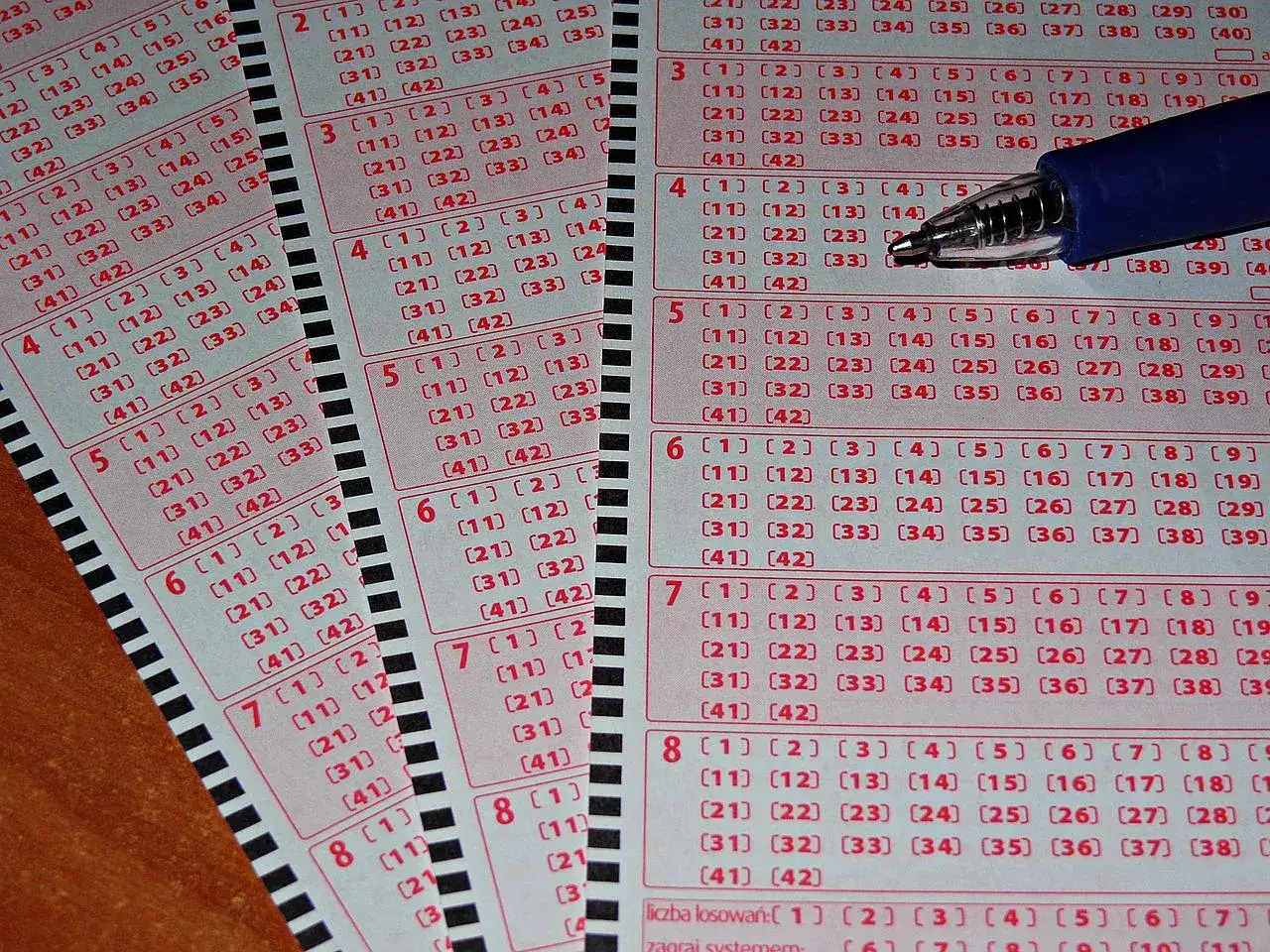 Kupony lotto multi multi z zaznaczonymi liczbami i niebieskim długopisem. Szansa na wygraną!