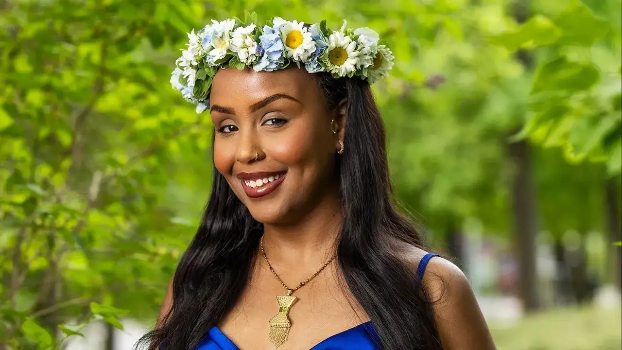Ayaan Ahmed bär en blomsterkrans och ett blått klänning.