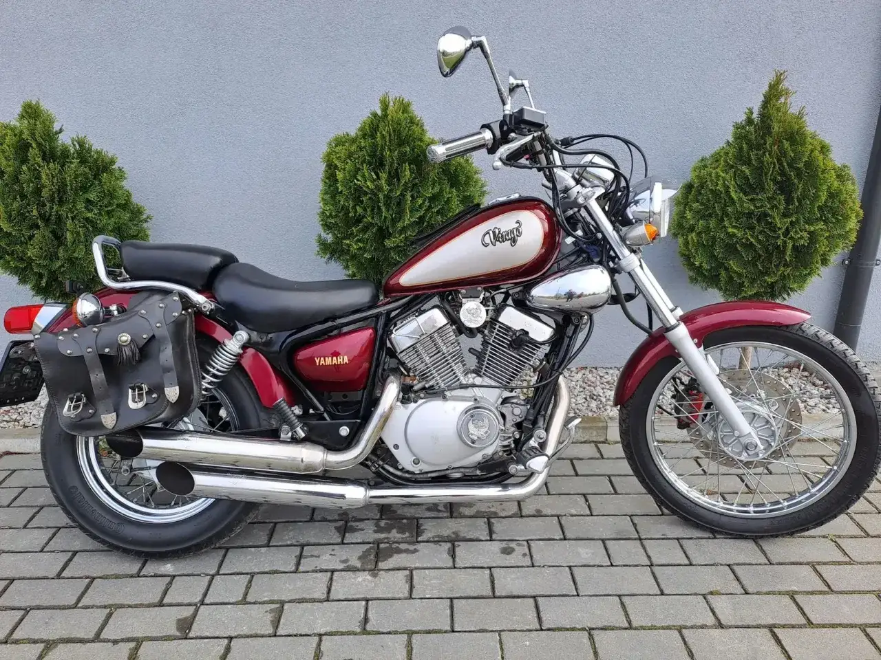Czerwony motocykl Yamaha Virago 125 z sakwami, idealny do miasta. Poznaj jego wymiary i możliwości.