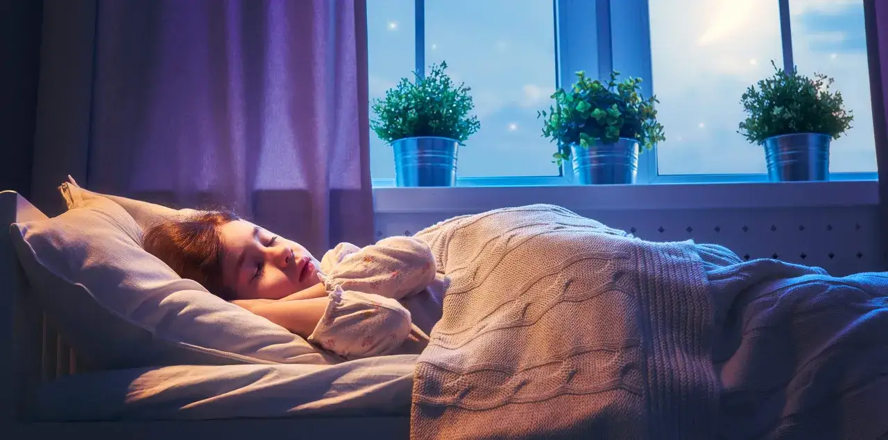 En liten flicka sover lugnt i sin säng. Frågan om hur många timmar ska en 10 åring sova är viktig för hennes välmående.
